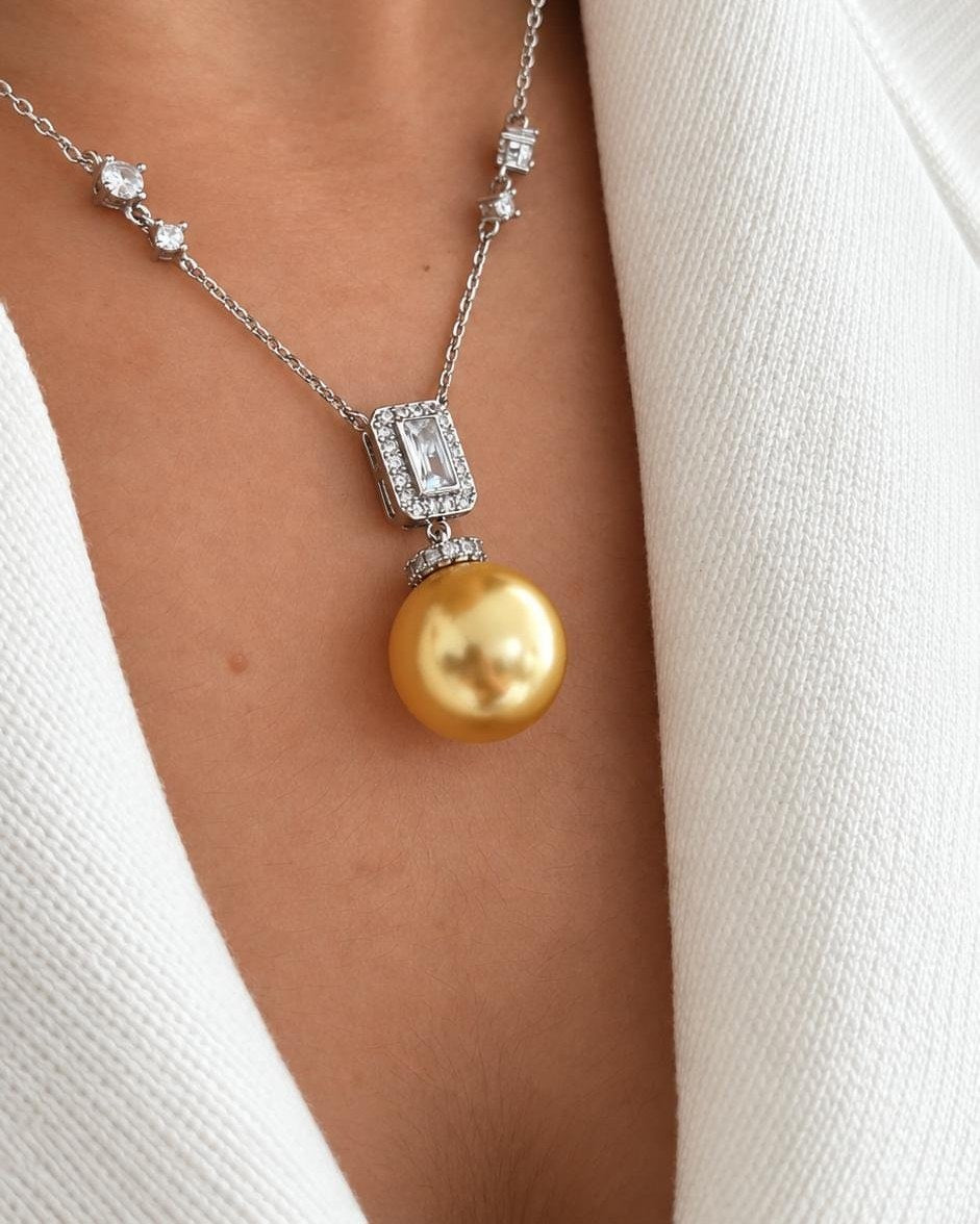 Echo necklace with a golden pearl drop, worn