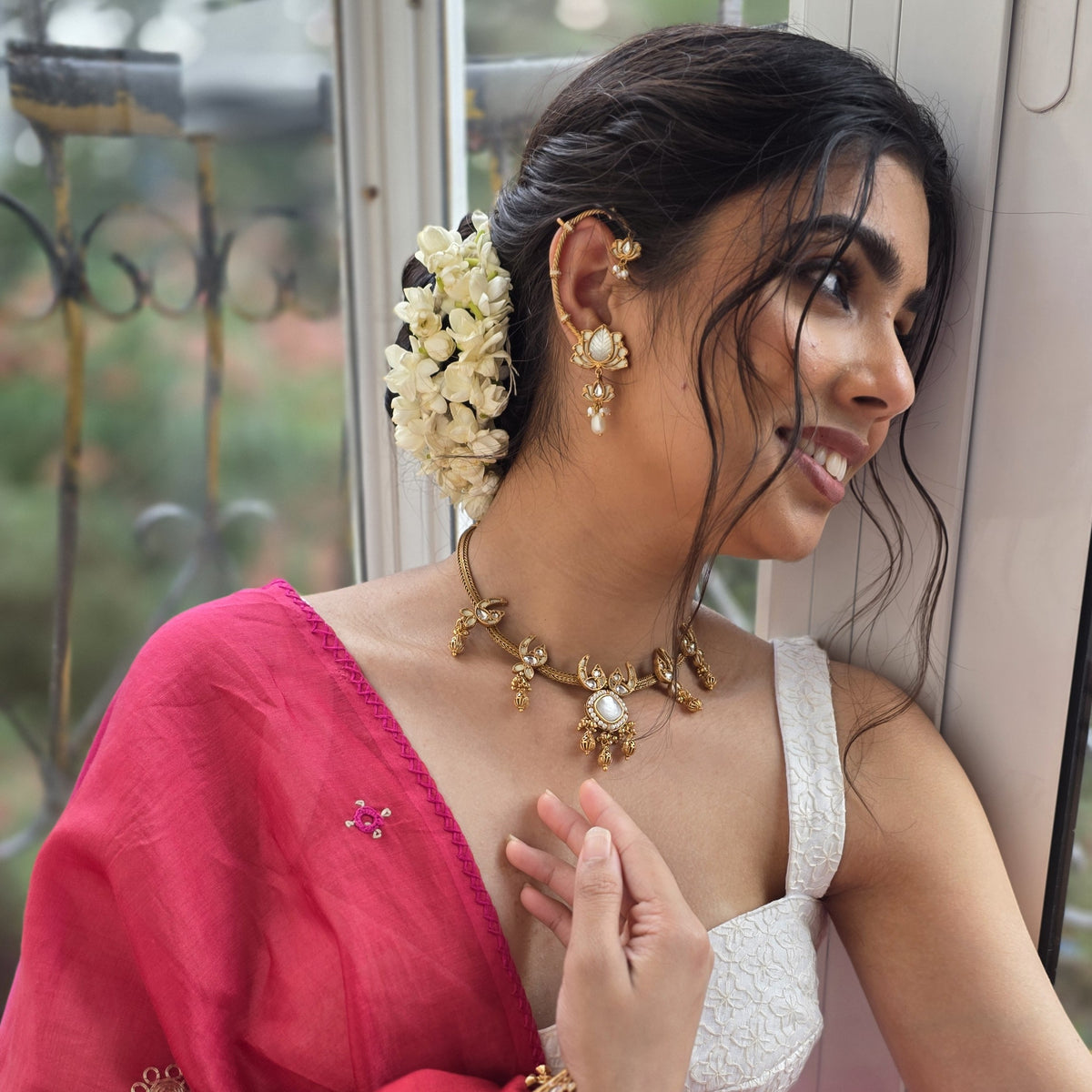 A customer at the studio window in a pink saree, wearing a Yuvaan necklace
