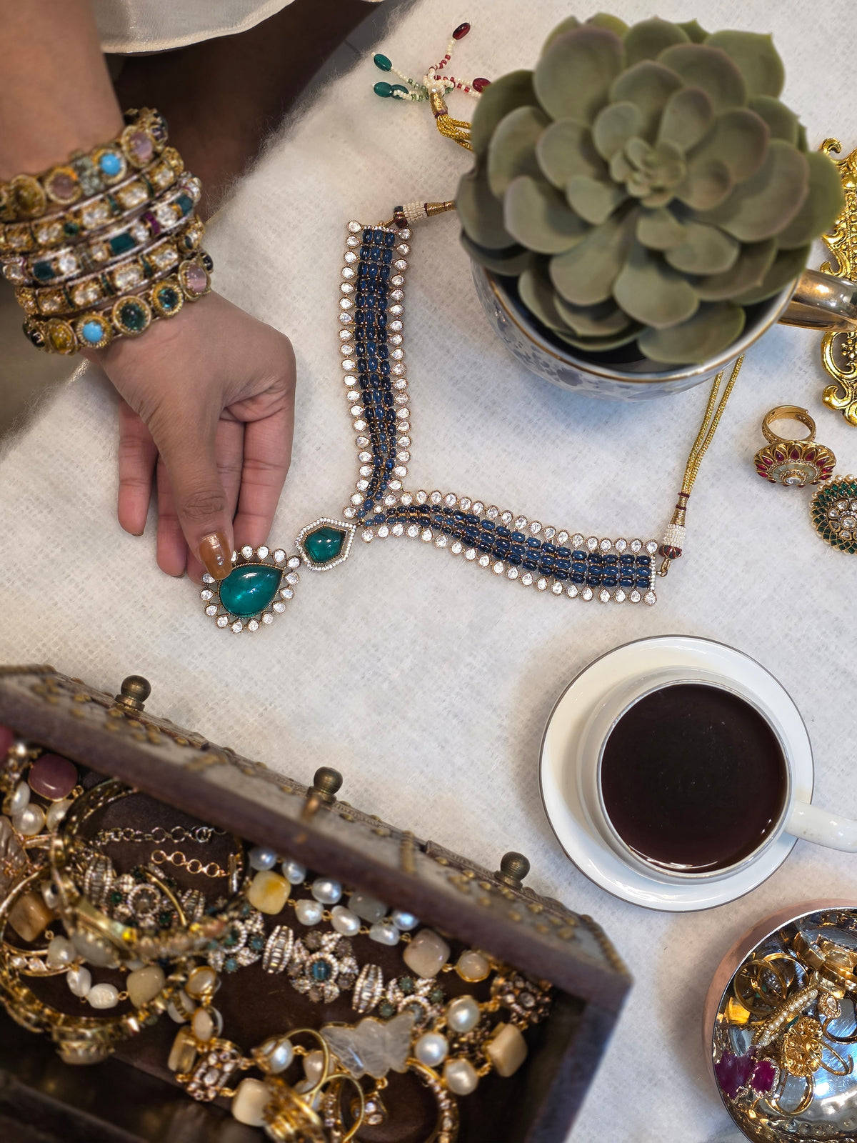The studio table: pieces, a coffee, a plant